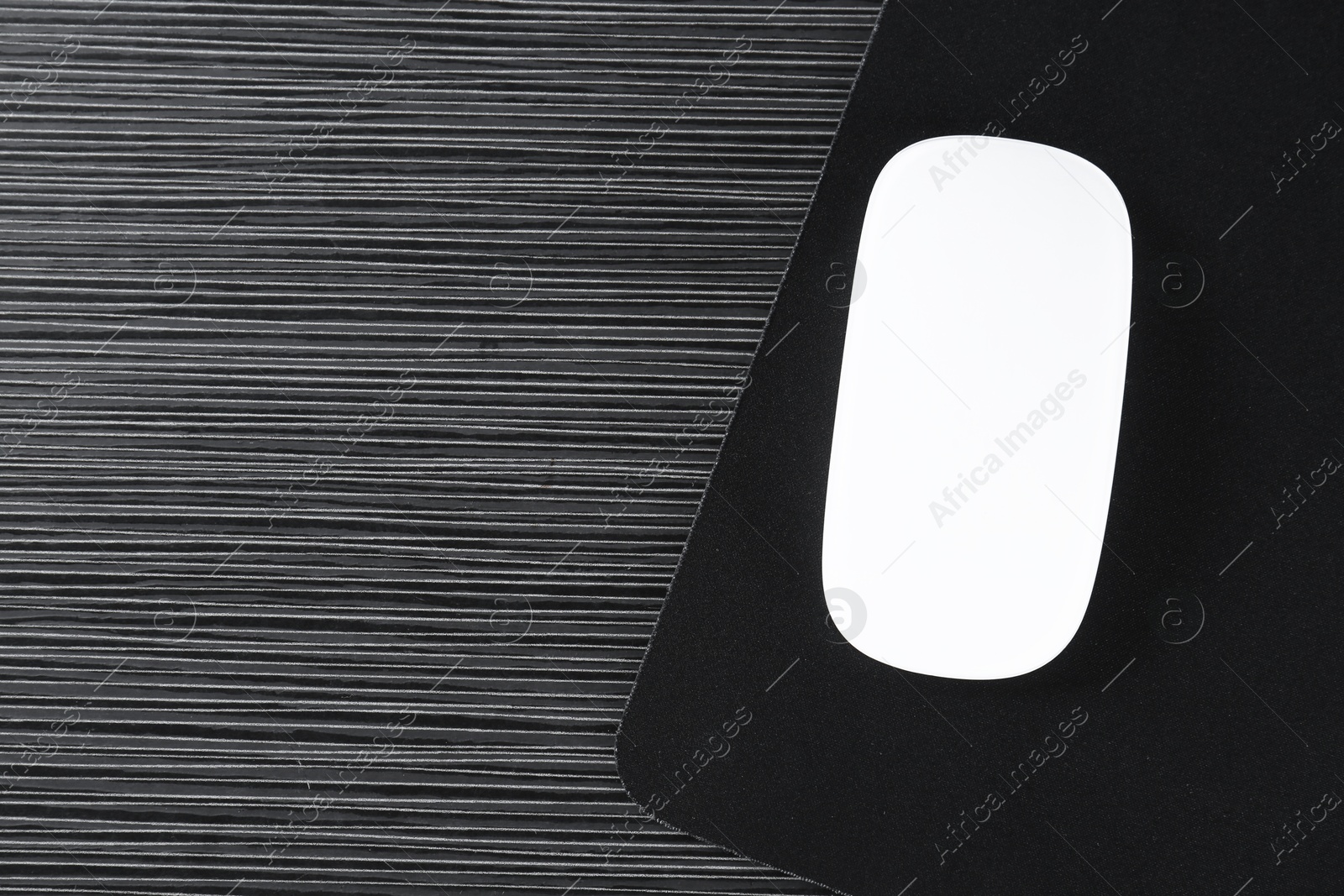 Photo of White computer mouse with mousepad on black wooden table, top view