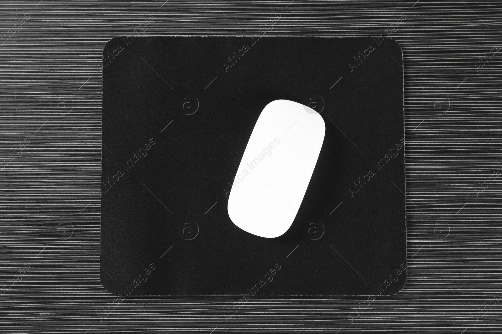 Photo of White computer mouse with mousepad on black wooden table, top view