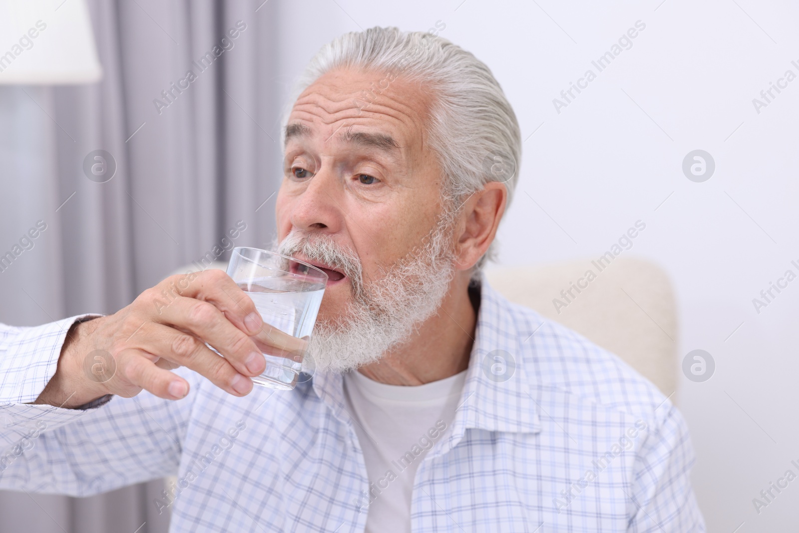 Photo of Handsome senior man drinking water at home