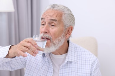 Photo of Handsome senior man drinking water at home