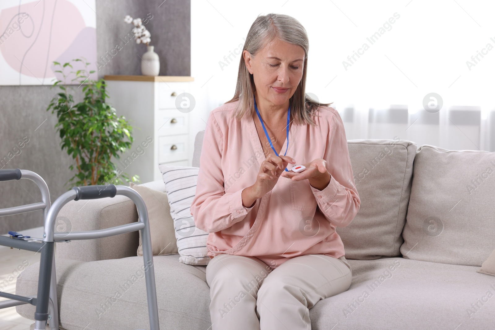 Photo of Senior woman pressing emergency call button at home