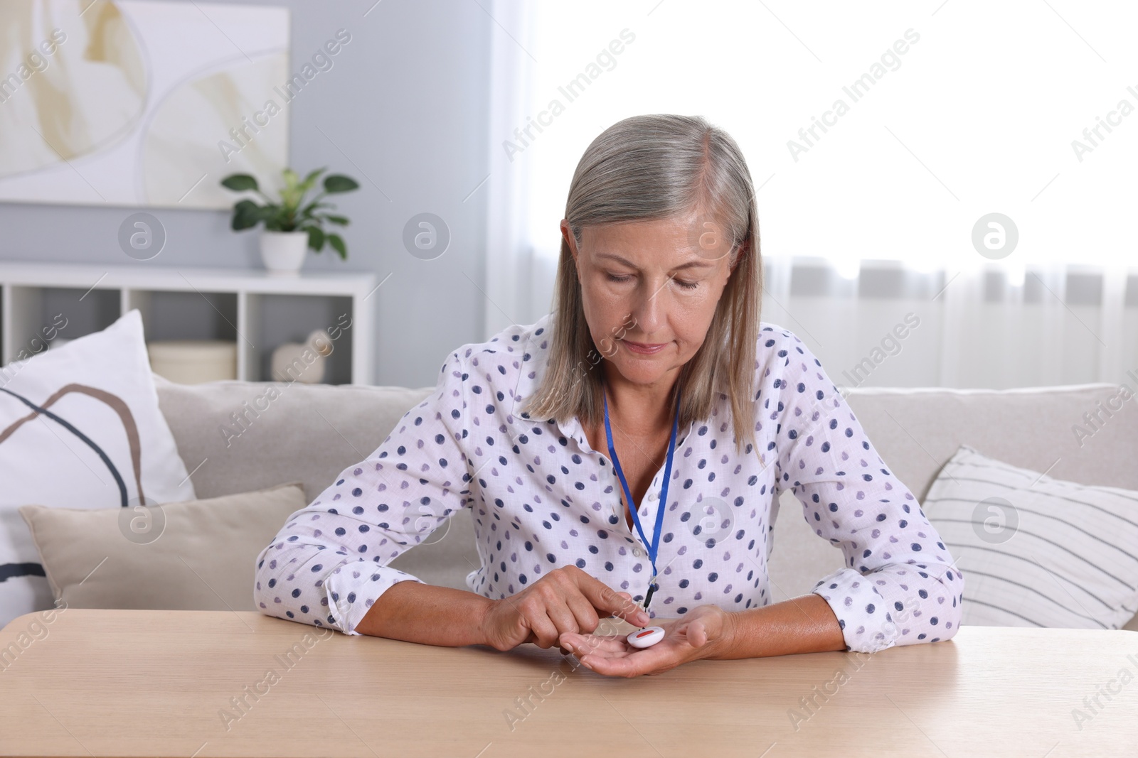 Photo of Senior woman pressing emergency call button at home