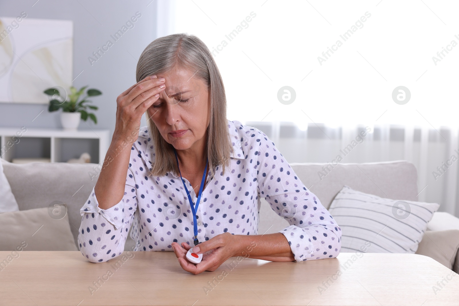 Photo of Senior woman suffering from headache pressing emergency call button at home