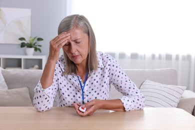 Photo of Senior woman suffering from headache pressing emergency call button at home