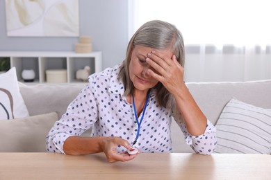 Photo of Senior woman suffering from headache pressing emergency call button at home