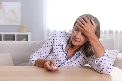 Photo of Senior woman suffering from headache pressing emergency call button at home