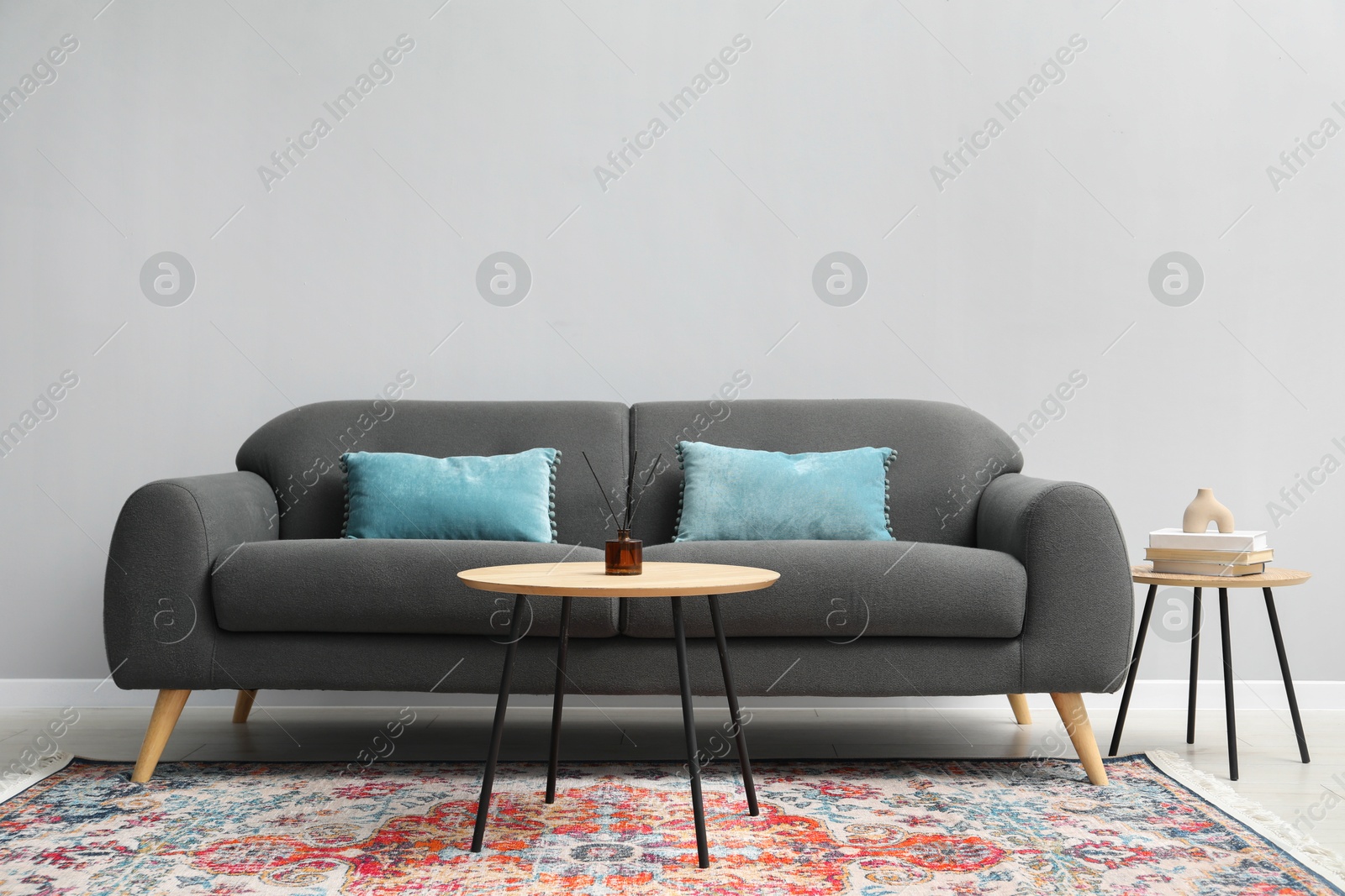 Photo of Comfortable sofa and tables near grey wall in room