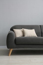 Photo of Comfortable sofa with cushions near grey wall in room