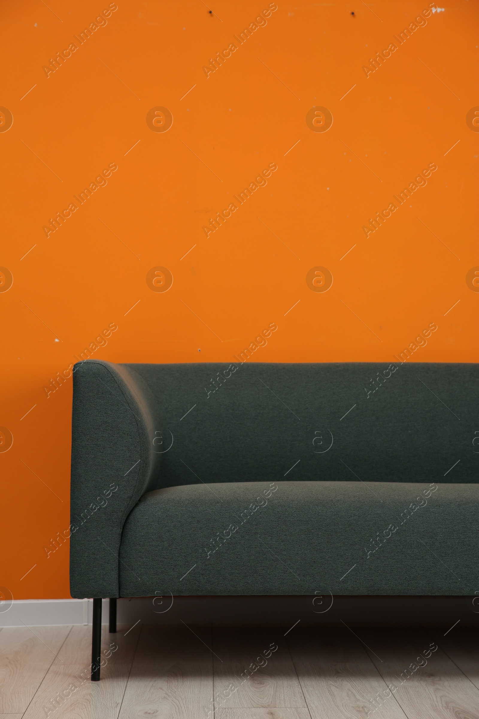 Photo of One stylish sofa near orange wall indoors