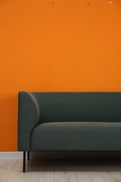 Photo of One stylish sofa near orange wall indoors