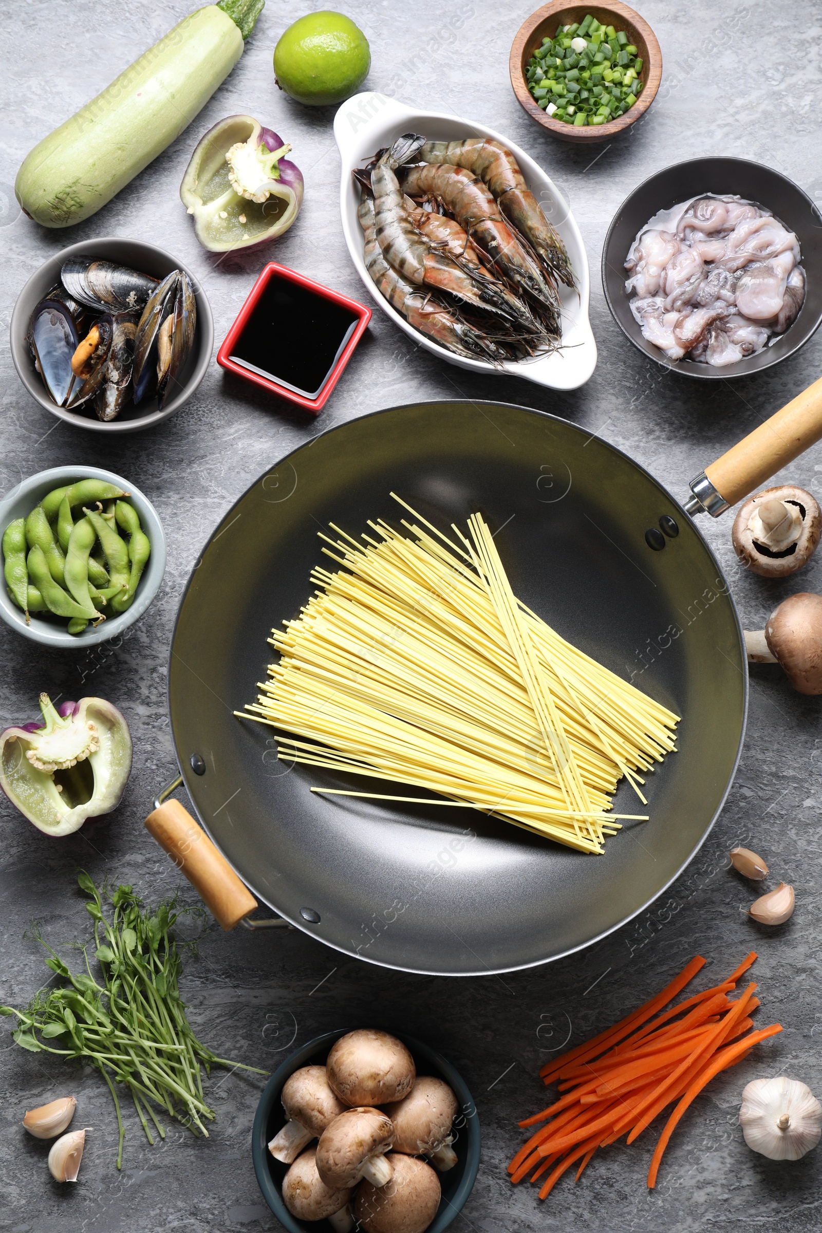 Photo of Different ingredients for wok on grey textured table, flat lay