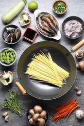 Photo of Different ingredients for wok on grey textured table, flat lay