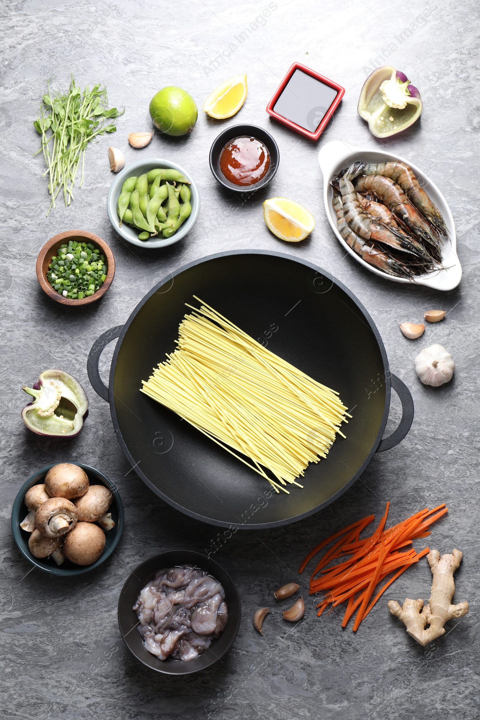 Photo of Different ingredients for wok on grey textured table, flat lay