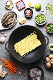 Photo of Different ingredients for wok on grey textured table, flat lay