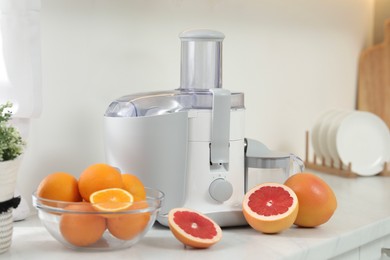 Modern juicer and grapefruits on white counter in kitchen