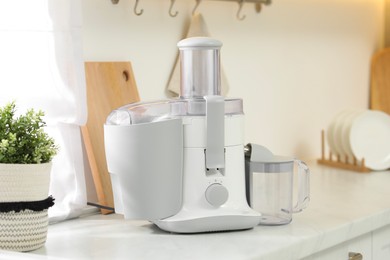 Photo of Modern juicer on white marble counter in kitchen