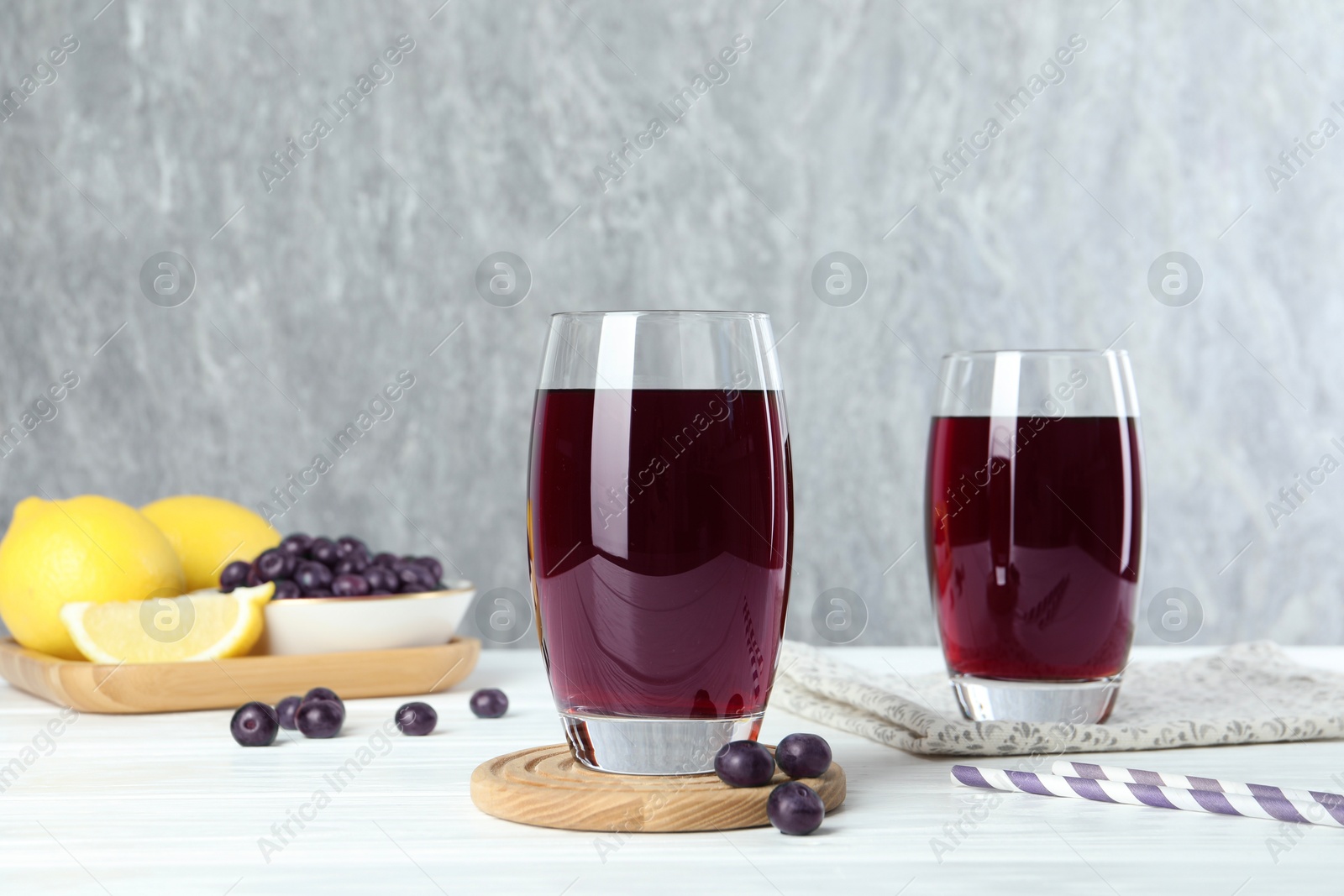 Photo of Tasty fresh acai juice in glasses with berries on white wooden table