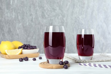 Tasty fresh acai juice in glasses with berries on white wooden table