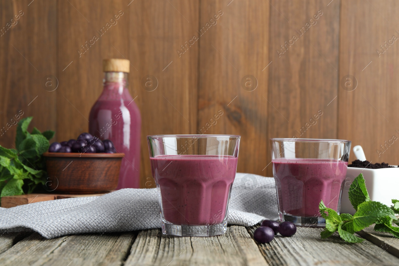 Photo of Tasty fresh acai juice in glasses with berries and mint on wooden table