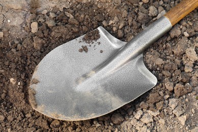 Photo of Metal shovel on soil outdoors, closeup. Gardening tool