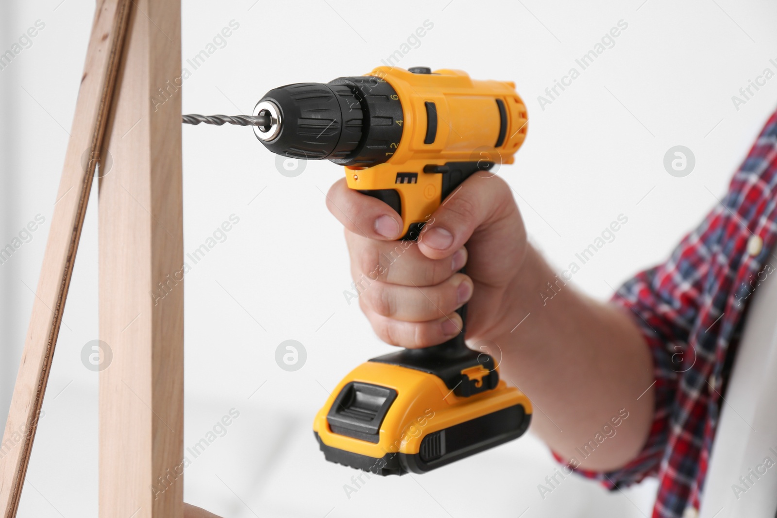 Photo of Man with electric screwdriver assembling furniture on white background, closeup