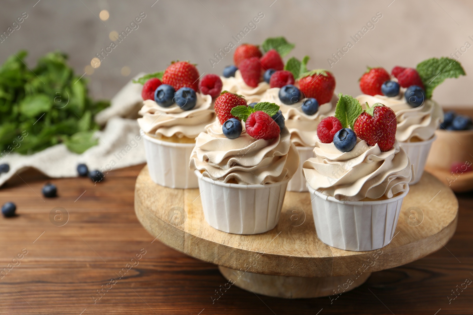 Photo of Tasty cupcakes with different berries and mint on wooden table, closeup. Space for text