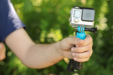 Man holding monopod with modern action camera outdoors, closeup