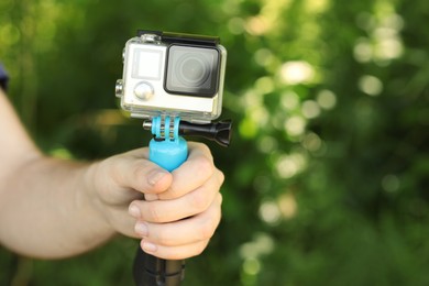 Photo of Man holding monopod with modern action camera outdoors, closeup. Space for text