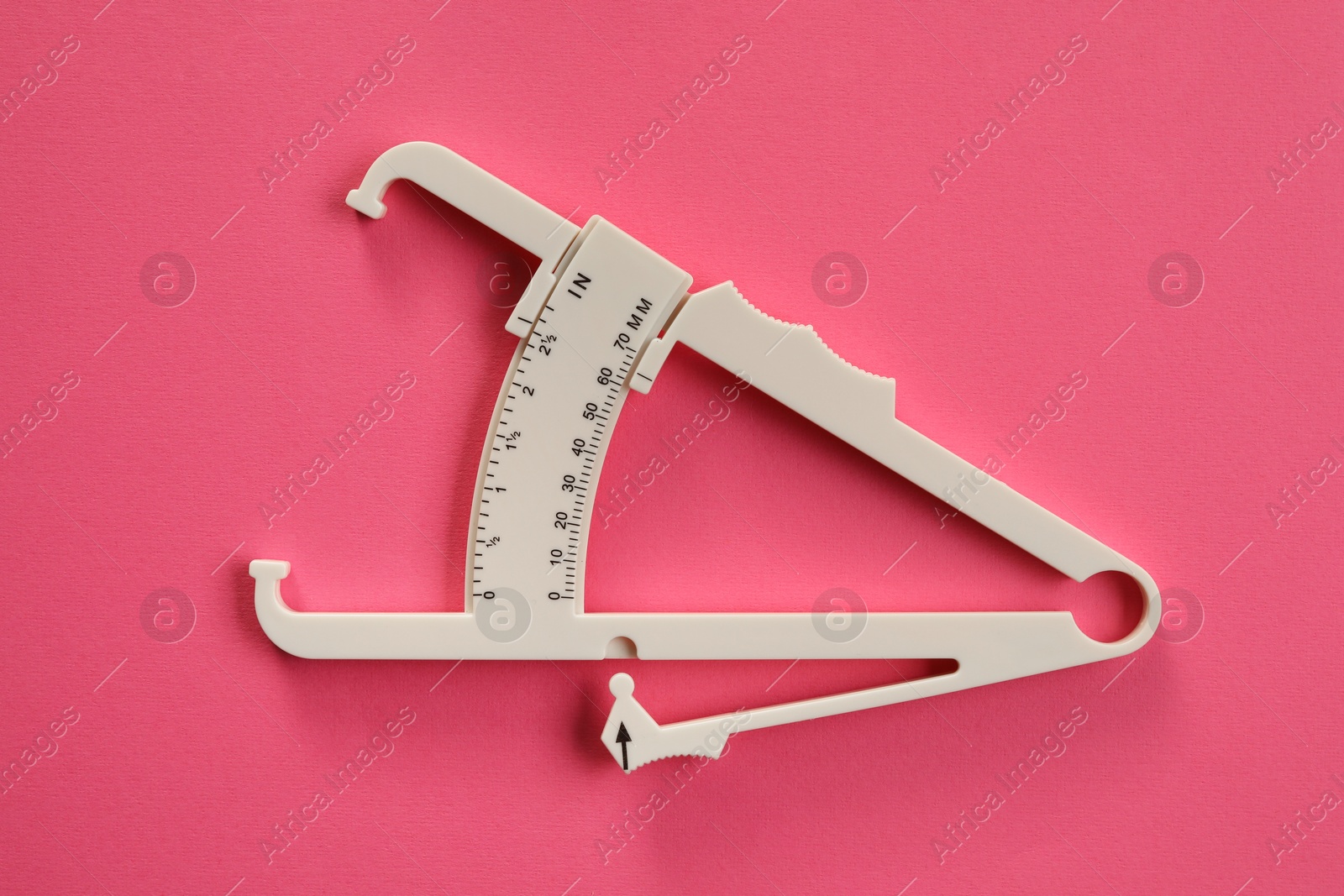 Photo of Plastic body fat caliper on pink background, top view