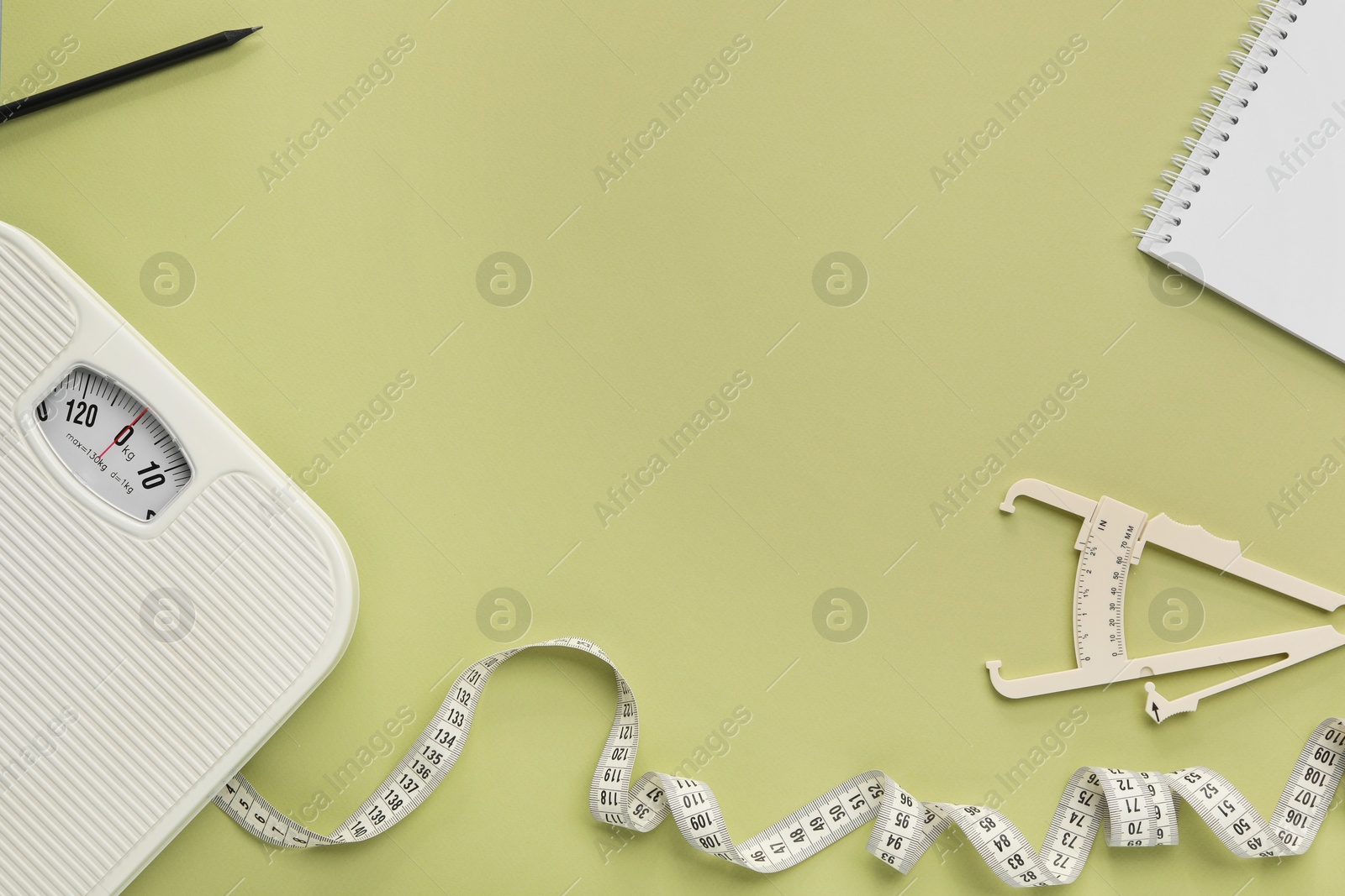 Photo of Body fat caliper, measuring tape, scale and notebook on light green background, flat lay. Space for text