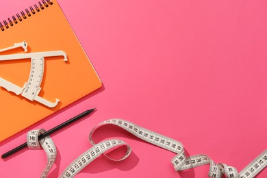 Photo of Body fat caliper, measuring tape, notebook and pencil on pink background, flat lay. Space for text