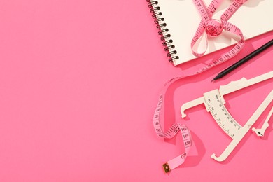 Photo of Body fat caliper, measuring tape, notebook and pencil on pink background, flat lay. Space for text