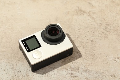 Photo of Modern action camera on stone surface, space for text