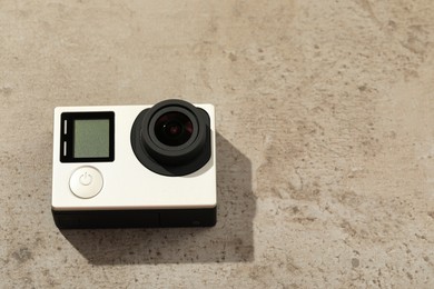 Modern action camera on stone surface, space for text