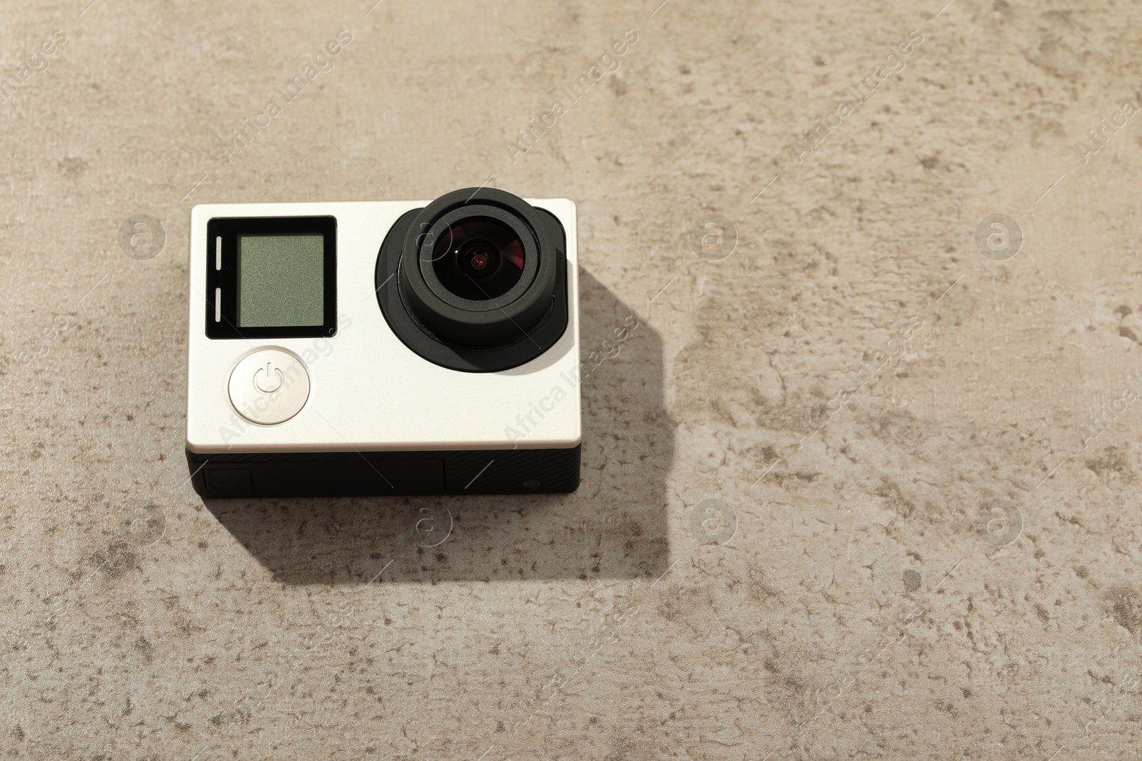 Photo of Modern action camera on stone surface, space for text