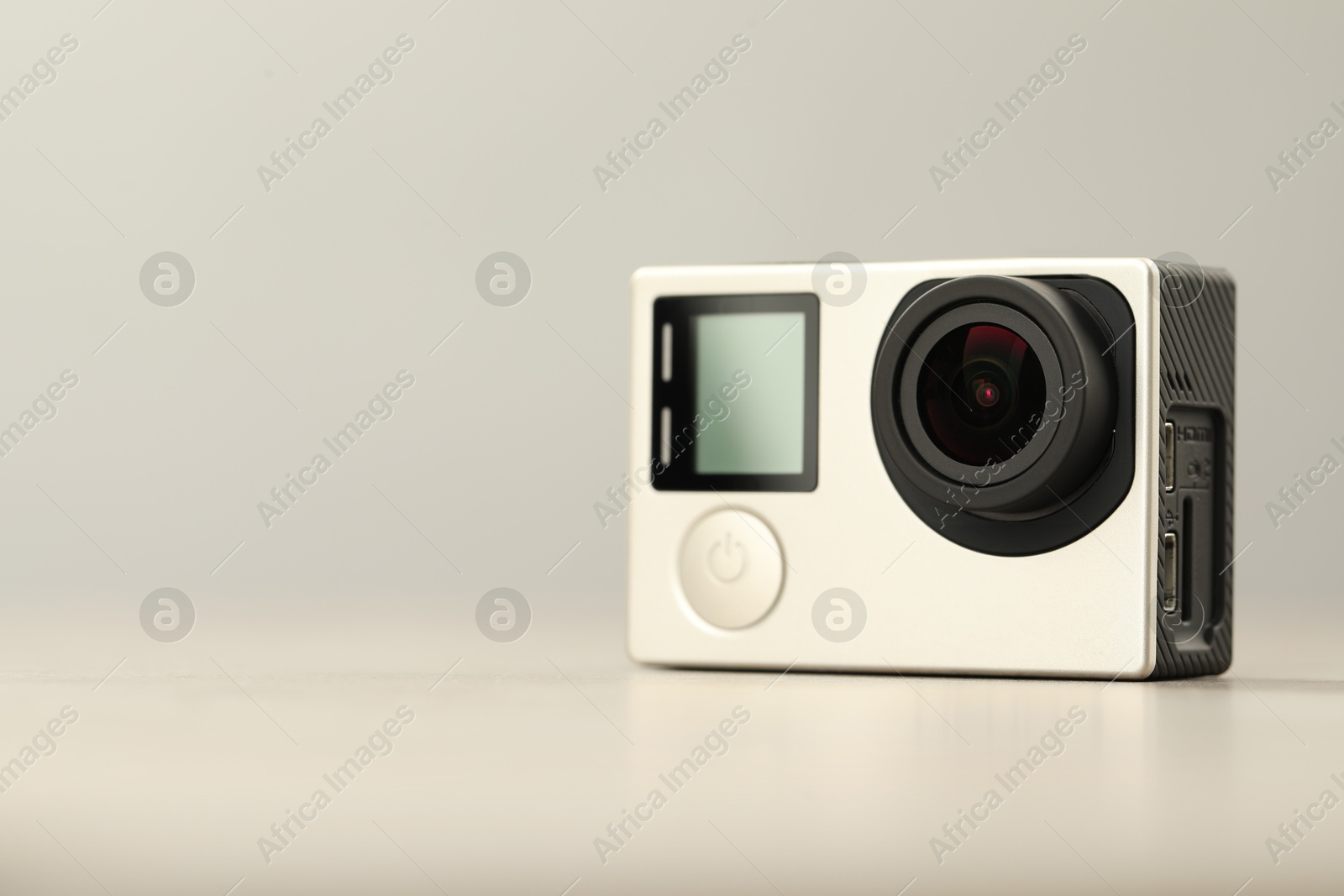 Photo of Modern action camera on light background, closeup. Space for text