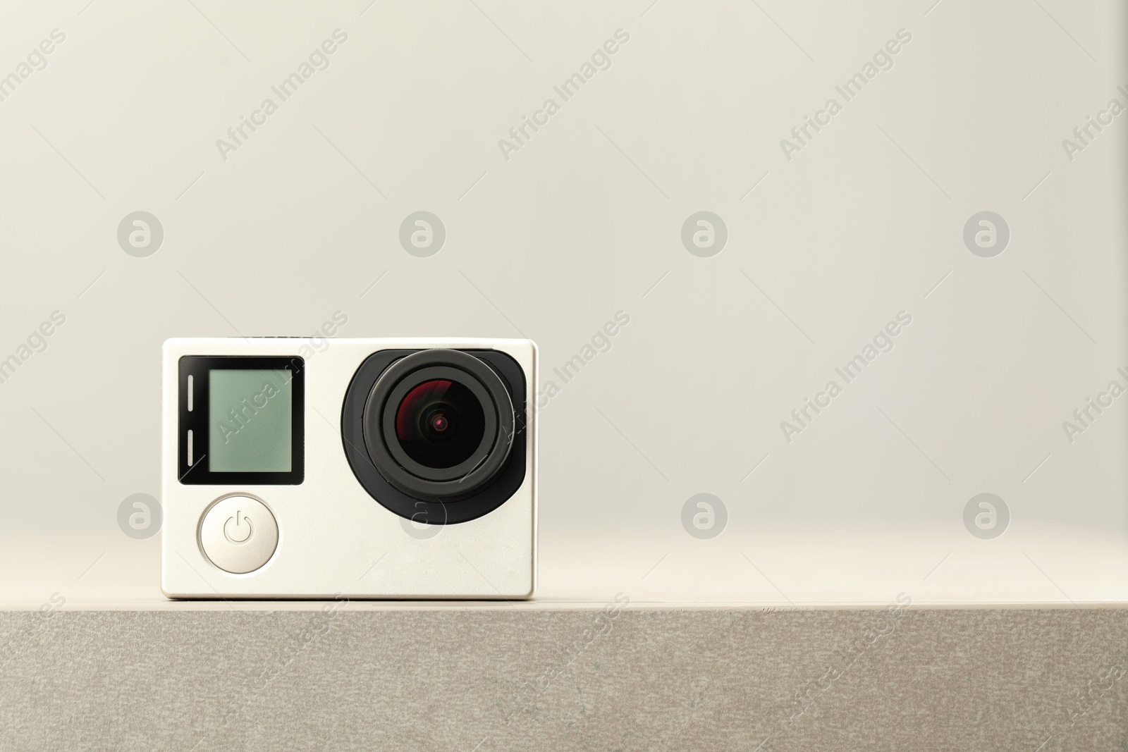 Photo of Modern action camera on stone surface, space for text