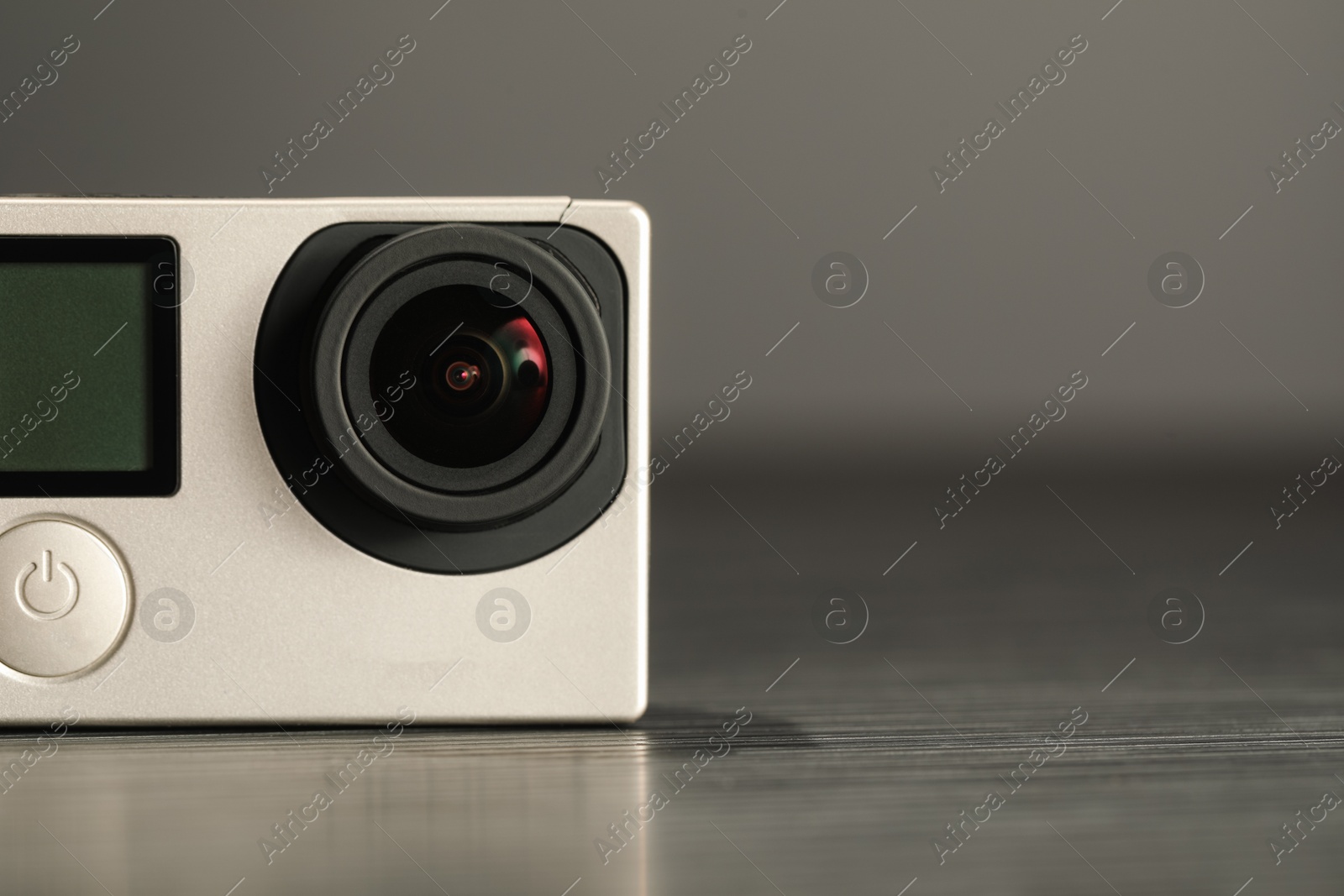 Photo of Modern action camera on wooden table against black background, closeup. Space for text