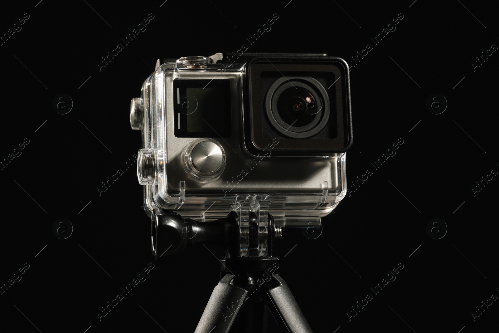 Photo of Modern action camera and tripod against black background, closeup