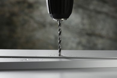 Photo of Drilling hole in plank on table against gray background, closeup