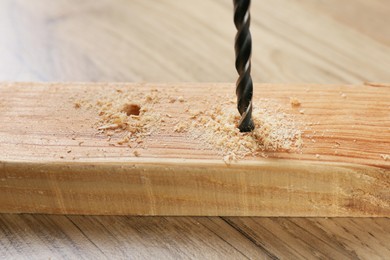 Photo of Drilling hole in plank on wooden table, closeup