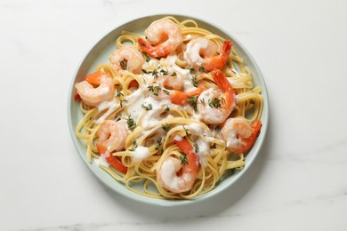 Photo of Delicious pasta with shrimps and creamy sauce on white marble table, top view