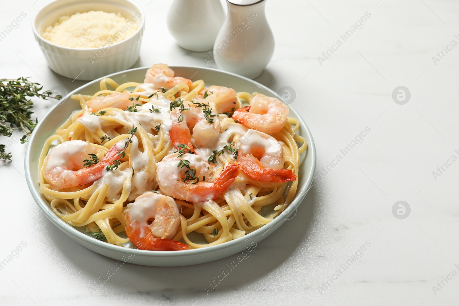 Photo of Delicious pasta with shrimps and creamy sauce on white table. Space for text