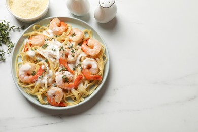 Photo of Delicious pasta with shrimps and creamy sauce on white marble table, flat lay. Space for text