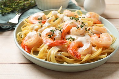 Photo of Delicious pasta with shrimps and creamy sauce on light wooden table, closeup