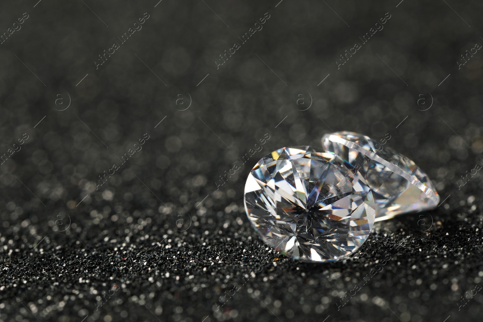 Photo of Beautiful dazzling diamonds on dark shiny background, closeup. Space for text