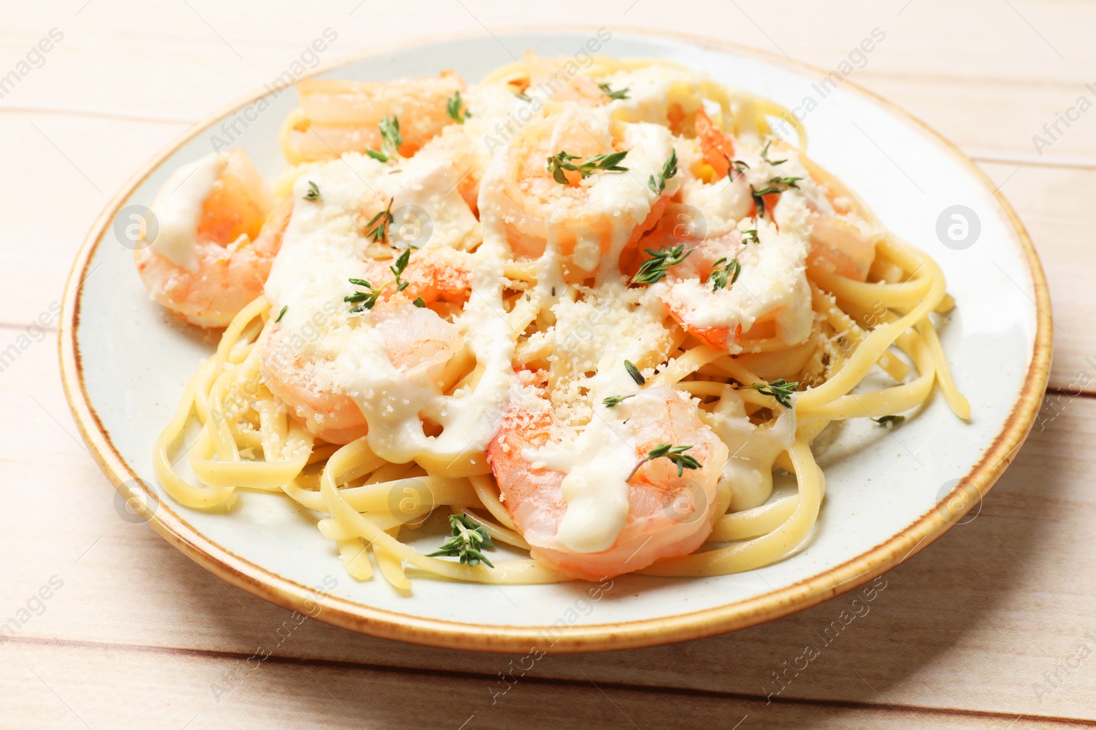 Photo of Tasty pasta with shrimps, creamy sauce and cheese on light wooden table, closeup