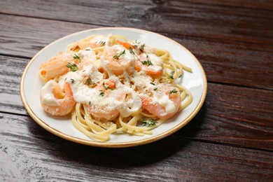 Photo of Tasty pasta with shrimps, creamy sauce and cheese on wooden table, closeup