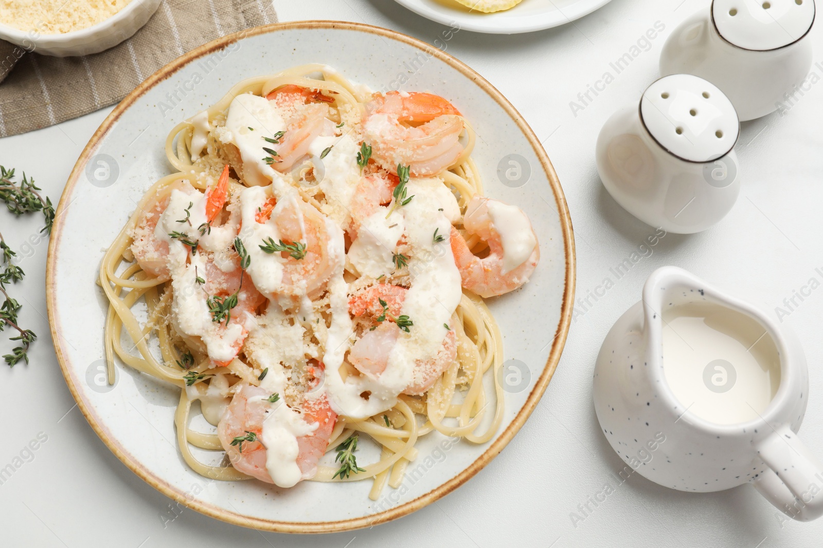 Photo of Tasty pasta with shrimps, creamy sauce and cheese served on white table, flat lay