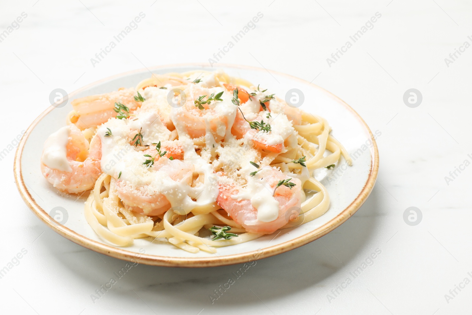 Photo of Tasty pasta with shrimps, creamy sauce and cheese on white marble table, closeup